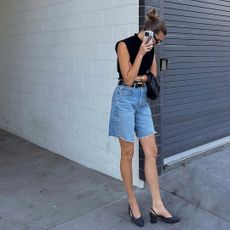 Woman on the phone wearing denim shorts, black top, and slingbacks