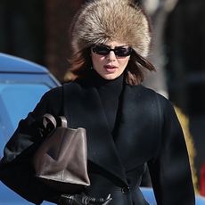 Kendall Jenner spotted in Aspen with Hailey Bieber and Fai Khadra on January 15, 2025 wearing an hourglass blazer by Ala&iuml;a with black Commando leggings and knee-high riding boots from Ann Demeulemeester. She accessorized with sunglasses, a brown fur hat, and a brown The Row bag.