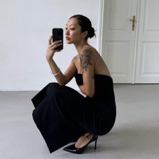Model taking a mirror selfie wearing a black strapless Zara ZW Collection Strapless Dress and chic black heels.