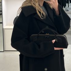 Eliza Huber carrying the new black suede Ala&iuml;a Le Teckel clutch in the brand's Paris flagship store. 